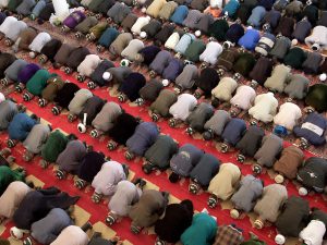 Muslim men bow to the east for Islamic prayers.